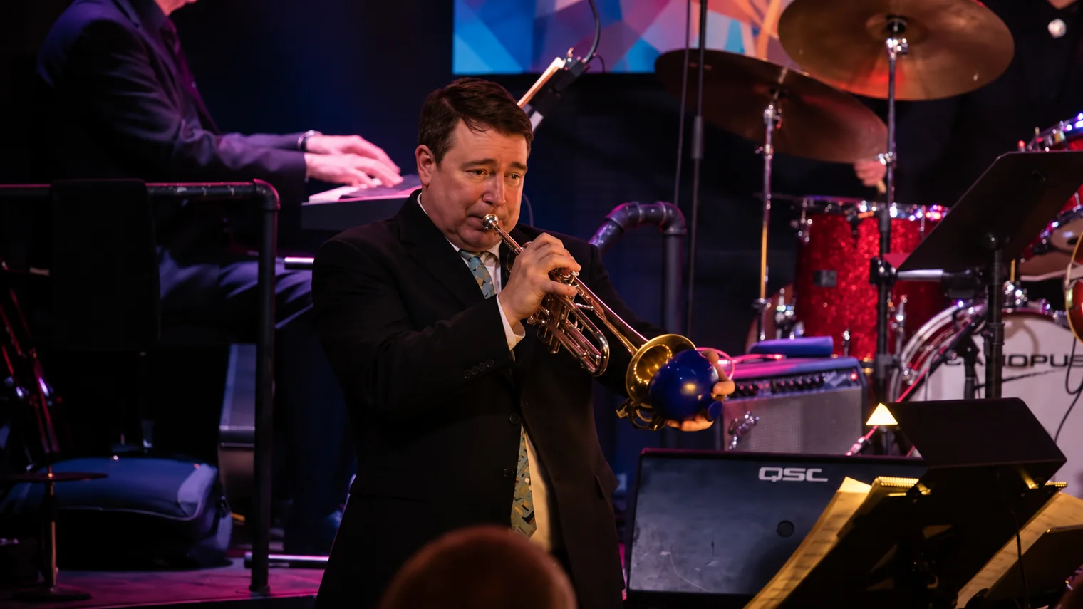 Chad Willis playing trumpet with a blue mute — approved editorial image
